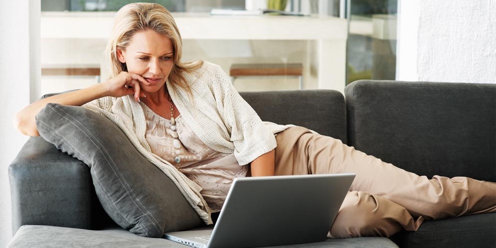 a woman sitting on a couch while using a laptop